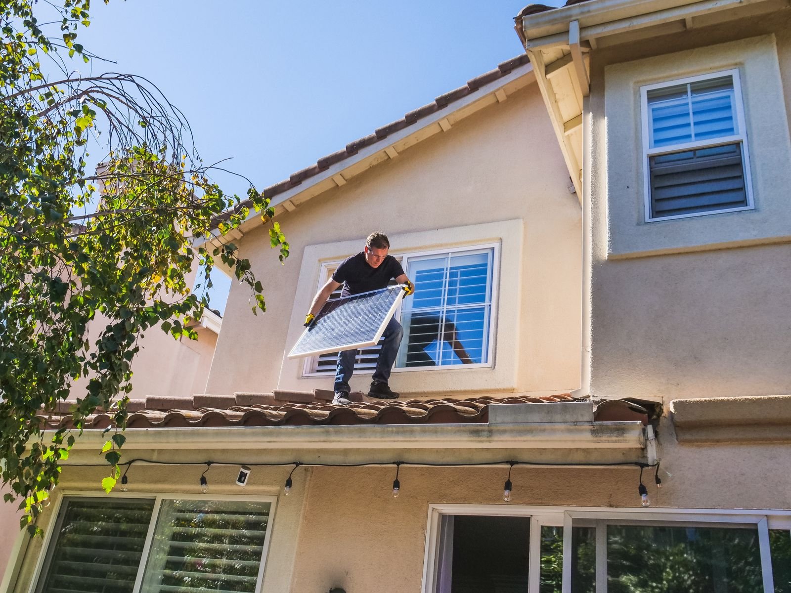 Solar Technician Installing Panel on House Roof